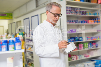 Focused pharmacist writing on box of medicine