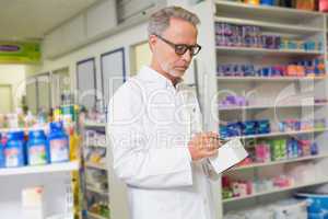 Focused pharmacist writing on box of medicine