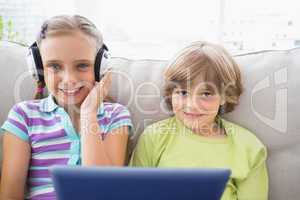 Boy playing music on laptop for sister in living room