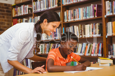 Teacher assisting boy with homework in library