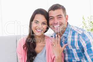 Happy young woman showing ring while sitting with man
