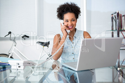Casual young woman using telephone and laptop