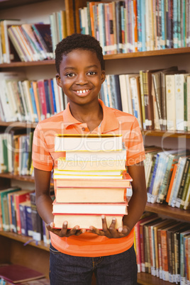 Portrait of cute boy carrying books in library