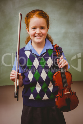 Cute little girl holding violin in classroom