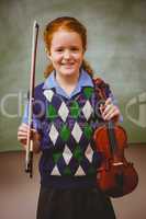 Cute little girl holding violin in classroom