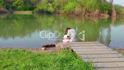 Mother Hugging Daughter And Looking At Natural Landscape Around Lake
