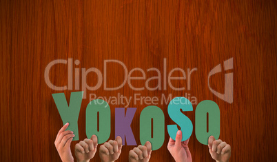 Composite image of hands holding up yokoso