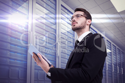 Composite image of businessman looking away while using tablet