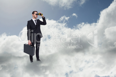 Composite image of businessman holding a briefcase while using b