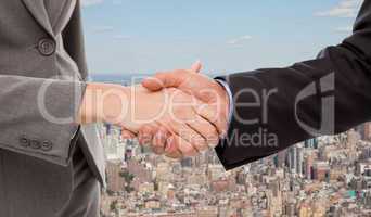 Composite image of close up of two businesspeople shaking their