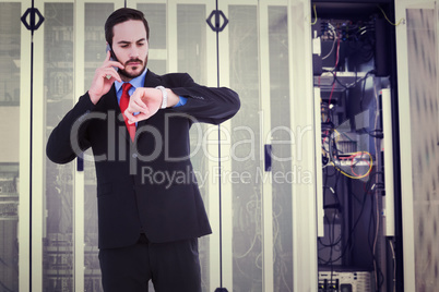 Composite image of serious businessman checking the time while o
