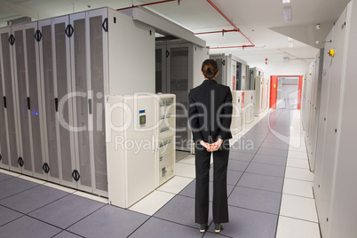 Composite image of businesswoman standing with hands behind back