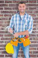 Composite image of portrait of confident repairman holding hamme