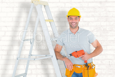 Composite image of happy handyman with power drill leaning on la