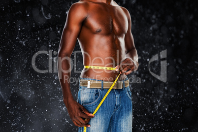 Composite image of mid section of a fit shirtless man measuring