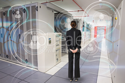 Composite image of businesswoman standing with hands behind back