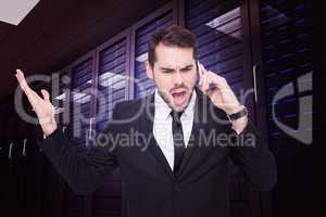 Composite image of angry businessman gesturing on the phone