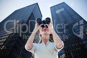 Composite image of businesswoman looking through binoculars
