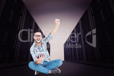 Composite image of handsome hipster using tablet pc and cheering
