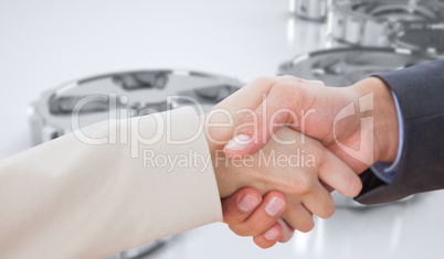 Composite image of close up on partners shaking hands