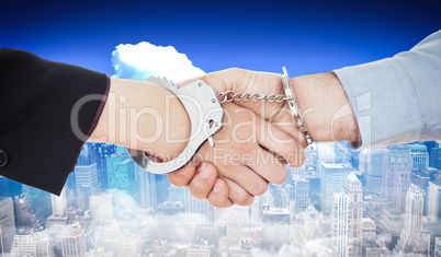 Composite image of business people in handcuffs shaking hands