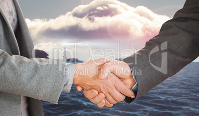 Composite image of two people having a handshake in an office