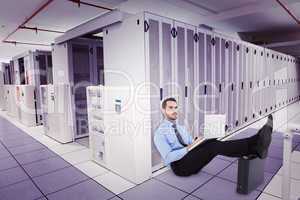 Composite image of businessman sitting on the floor with feet up