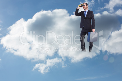 Composite image of businessman looking through binoculars holdin