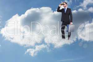 Composite image of businessman looking through binoculars holdin