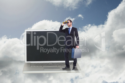 Composite image of businessman looking through binoculars holdin