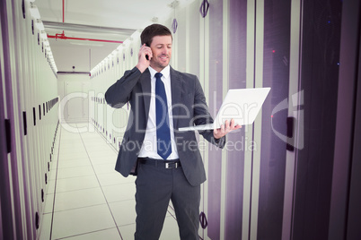 Composite image of businessman talking on phone holding laptop