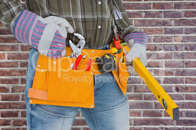 Composite image of handyman holding spirit level