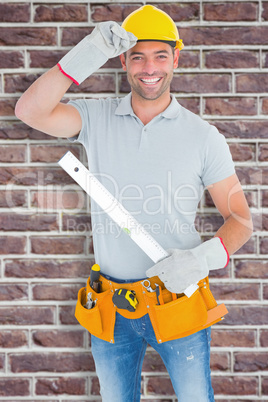 Composite image of smiling handyman holding spirit level
