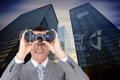 Composite image of businessman holding binoculars