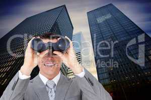 Composite image of businessman holding binoculars