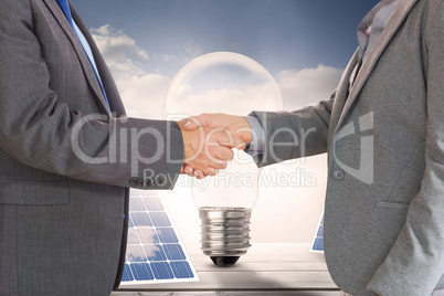 Composite image of close up on two businesspeople shaking hands
