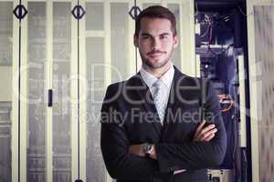 Composite image of smiling businessman posing with arms crossed