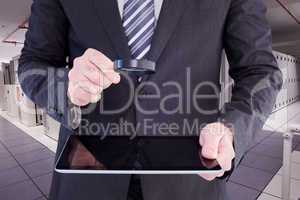 Composite image of businessman looking at tablet with magnifying