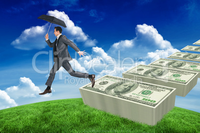 Composite image of businessman jumping holding an umbrella