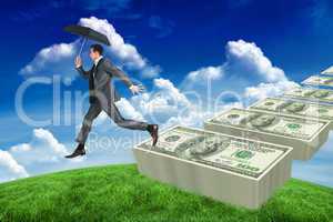 Composite image of businessman jumping holding an umbrella