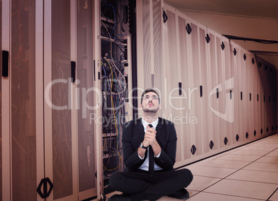 Composite image of businessman sitting praying and looking up