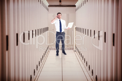 Composite image of businessman on the phone holding laptop