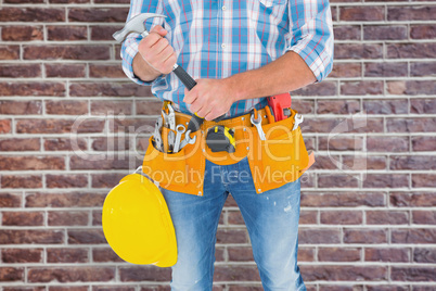 Composite image of midsection of manual worker holding hammer