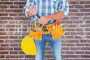 Composite image of midsection of manual worker holding hammer