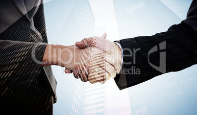 Composite image of close up of two businesspeople shaking their