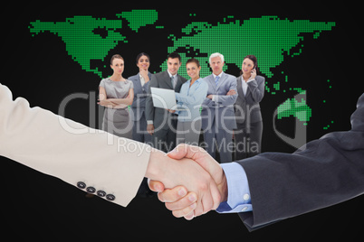 Composite image of smiling business people shaking hands while l