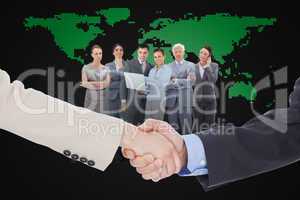 Composite image of smiling business people shaking hands while l