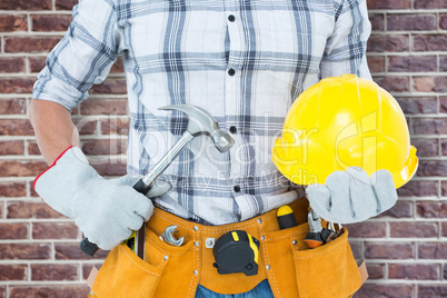 Composite image of handyman holding hammer and hard hat