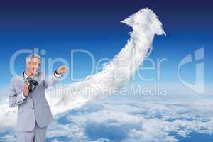 Composite image of businessman holding binoculars and pointing o
