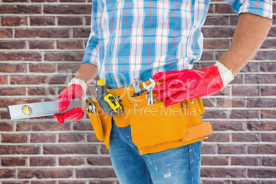 Composite image of midsection of handyman holding spirit level